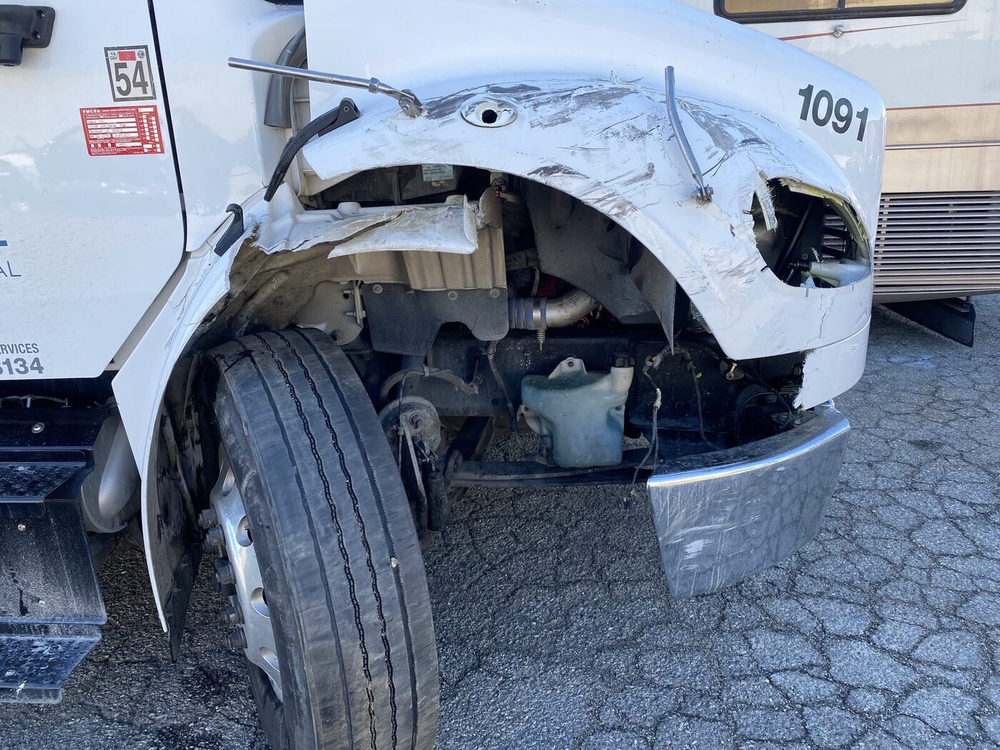 World Oil Freightliner 1091 with front-left collision damage to fender, hood and bumper