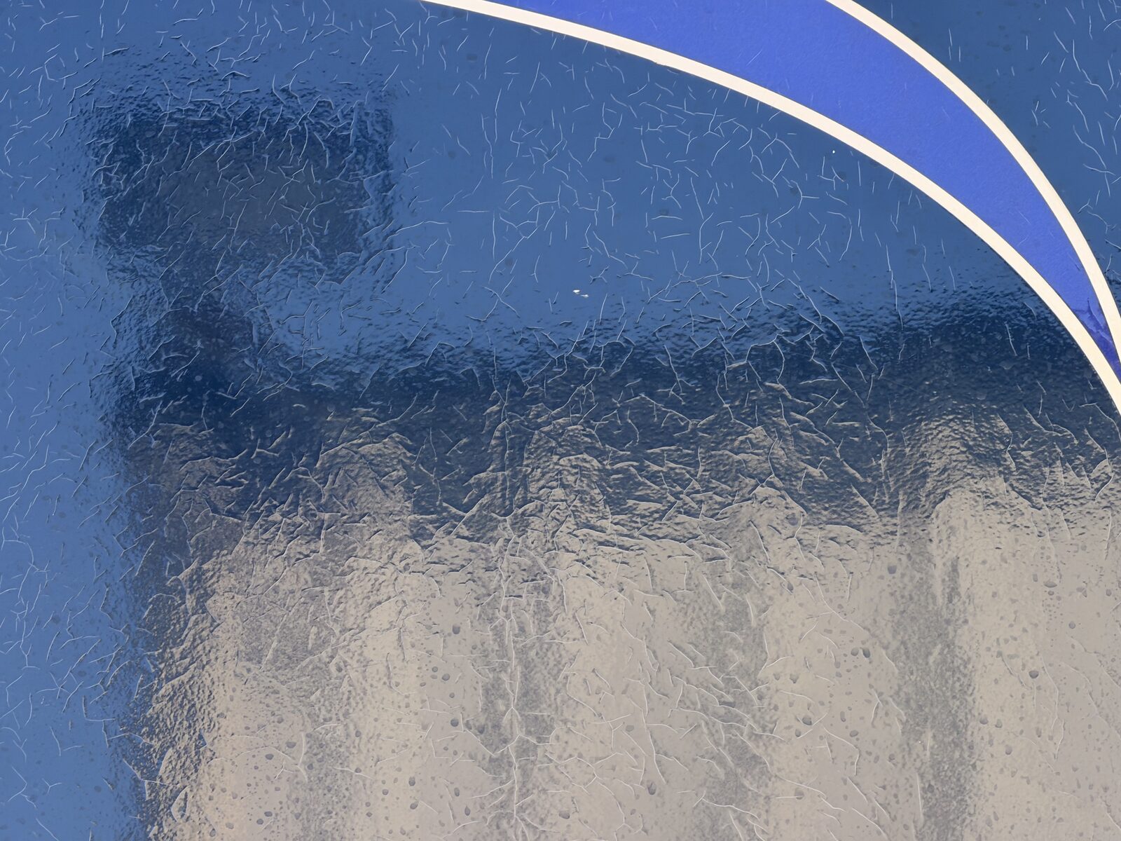 Close-up of thermal checking: fine web of cracks in a dark blue fiberglass motorhome sidewall